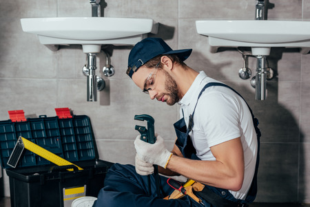 young professional plumber fixing sink in bathroomの写真素材