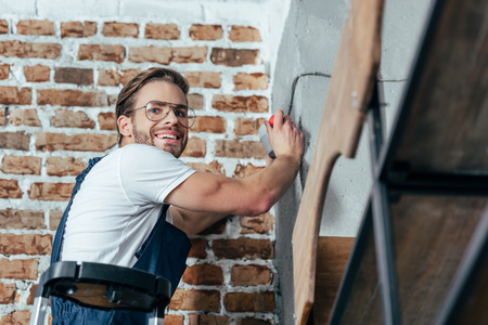 handsome young professional electrician smiling at cameraの写真素材