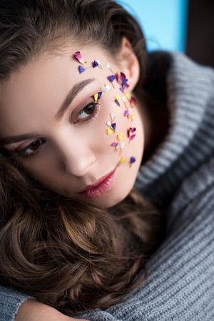close-up portrait of woman with flowers on face in warm sweaterの写真素材