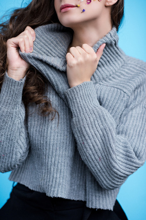 cropped shot of woman stretching neck of stylish sweater isolated on blueの写真素材