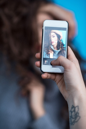 cropped shot of person using smartphone and photographing sensual young womanの写真素材