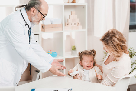 mother and crying  little daughter at doctors reception in clinicの写真素材