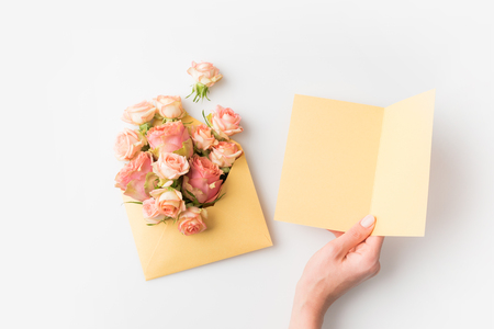 hand holding blank paper beside pink flowers in envelope isolated on whiteの写真素材