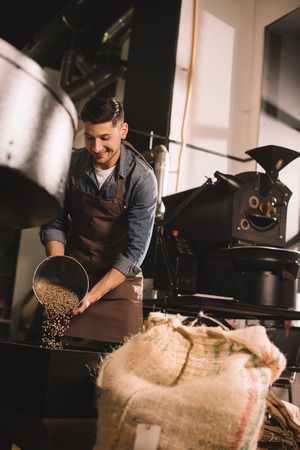 coffee roaster pouring coffee beans into roasting machine