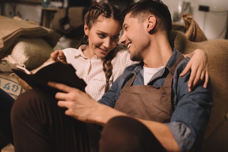 young coffee shop owners making notes in notebook while having discussionの写真素材