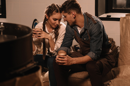 couple with cups of coffee having break during work at coffee shopの写真素材