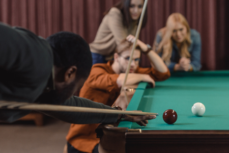 young african american man playing in pool at bar with friendsの写真素材