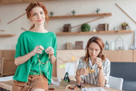 beautiful young women with handmade accessories in workshopの写真素材