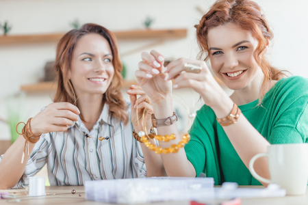 happy young women making necklace at workshopの写真素材