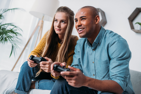 smiling multicultural couple playing video game at home