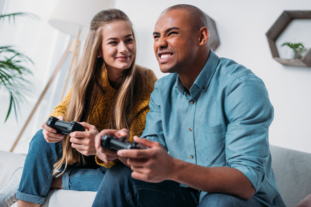 smiling multicultural couple playing video game at homeの写真素材