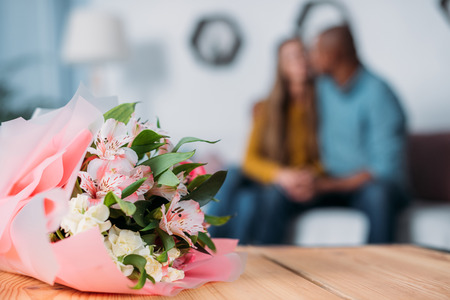 multicultural couple kissing with bouquet on foregroundの写真素材