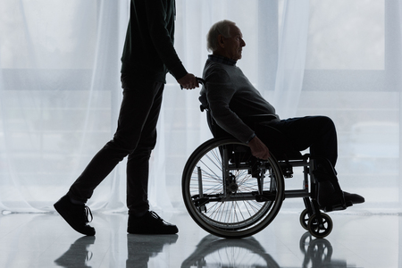 Young man helping senior man in wheelchairの写真素材