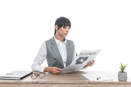 businesswoman sitting at table and reading business newspaper isolated on whiteの写真素材