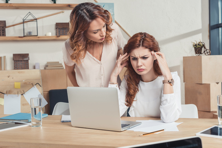 stressed young manageress looking at laptop while boss talking to herの写真素材