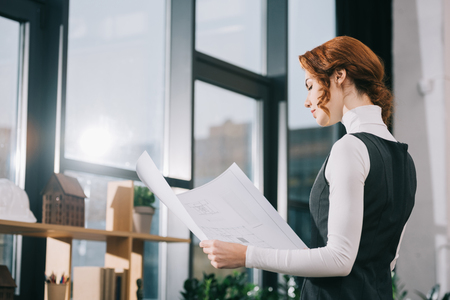 beautiful female architect looking at blueprint in modern officeの写真素材