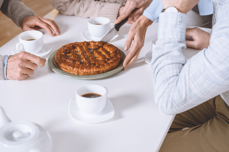 cropped image of woman cutting pie on table while friends sittingの写真素材