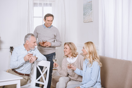 friends sitting on sofa and on chair while speaking in room