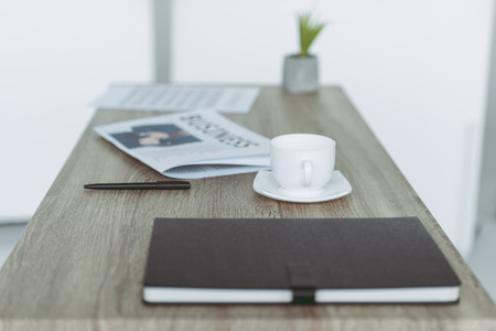 cup and notebook with pen on wooden table