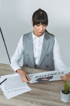 businesswoman reading newspaper isolated on grayの写真素材
