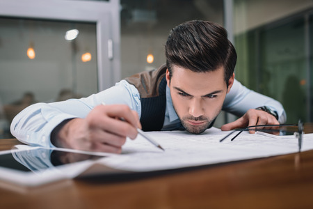 adult businessman working with blueprint in office
