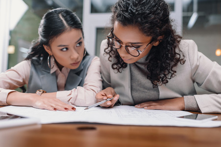 concentrated multiethnic businesswomen working with documents in officeの写真素材