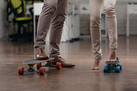 cropped view of businesspeople have fun with skateboards in officeの写真素材