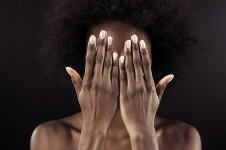 african american woman covering face with hands isolated on blackの写真素材
