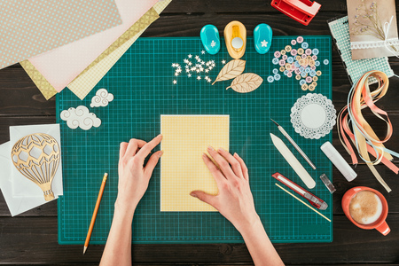 cropped image of designer sitting at working table with template for scrapbooking postcardの写真素材