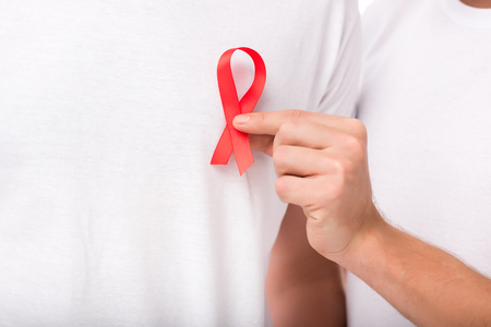 cropped shot of man attaching aids ribbon on t-shirt of partner isolated on white