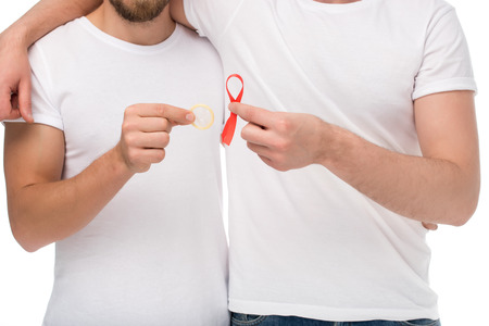 cropped shot of embracing gay couple with aids ribbon and condom isolated on whiteの写真素材