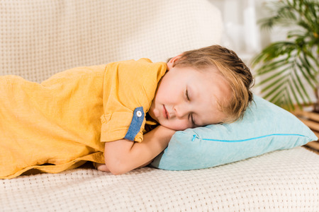 portrait of adorable little boy sleeping on sofa at homeの写真素材