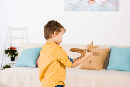 little adorable little boy playing with wooden toy airplane at homeの写真素材