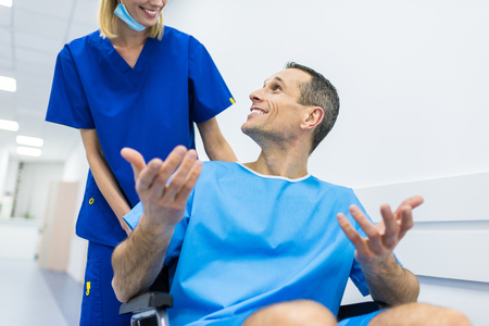 surgeon and smiling male patient in wheelchair in hospital corridorの写真素材