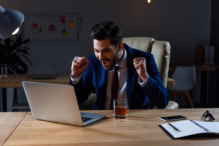 happy and surprised businessman looking at laptop and showing yes gestureの写真素材