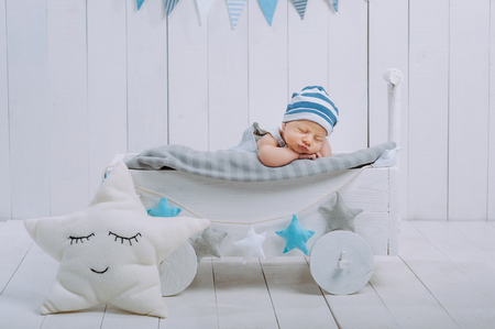 portrait of adorable infant baby in hat sleeping in wooden baby cot decorated with starsの写真素材