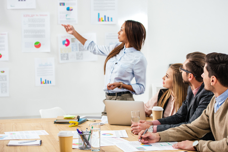 african american businesswoman pointing at papers on white board during meeting with multiethnic colleagues in officeの写真素材