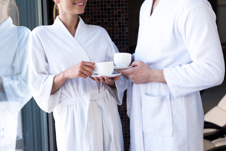 cropped shot of couple in bathrobes drinking tea in spa centerの写真素材