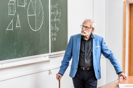 grey hair professor looking at blackboardの写真素材