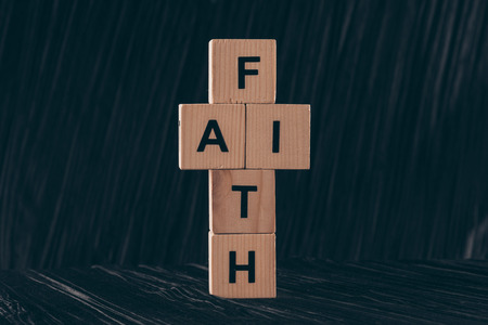 wooden cubes in shape of cross with word Faith on black tableの写真素材