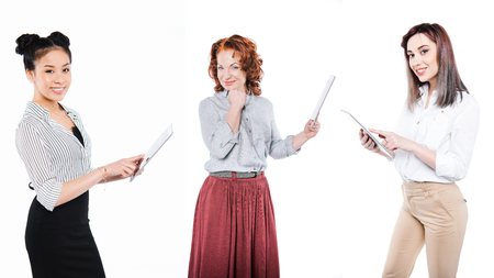 portrait of cheerful multicultural women with tablets isolated on whiteの写真素材