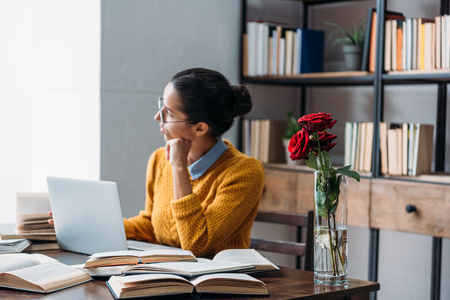 young student girl preparing for exam at library with red roses in vaseの写真素材