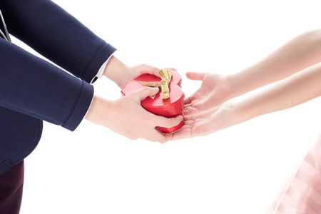 cropped shot of boy in suit presenting heart shaped gift box to little girl isolated on whiteの写真素材