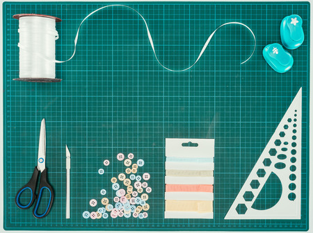 Top view of scissors, buttons and ribbon for scrapbooking decoration on turquoise scaleの写真素材