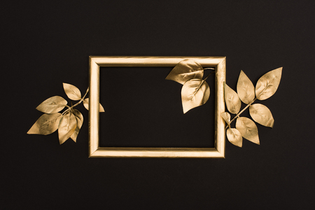 top view of golden photo frame and leaves isolated on blackの写真素材