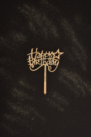 top view of golden happy birthday sign on black surfaceの写真素材