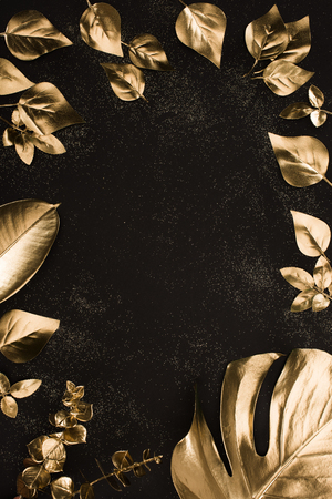 top view of set of different golden leaves on black surfaceの写真素材