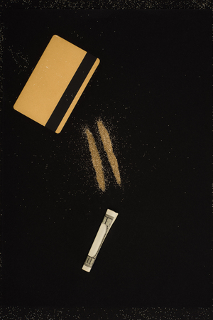 top view of golden credit card, dollar and powder lines isolated on black