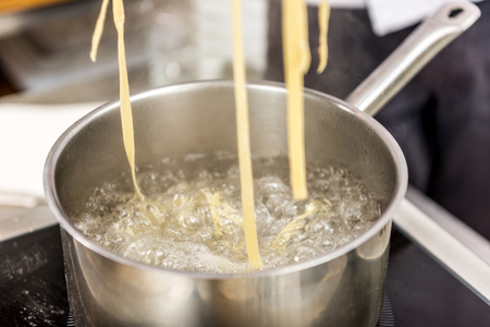 pasta in boiling water in pot on electric stoveの写真素材