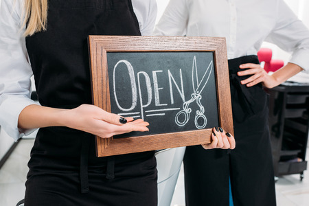 cropped image of hairdresser showing sign openの写真素材